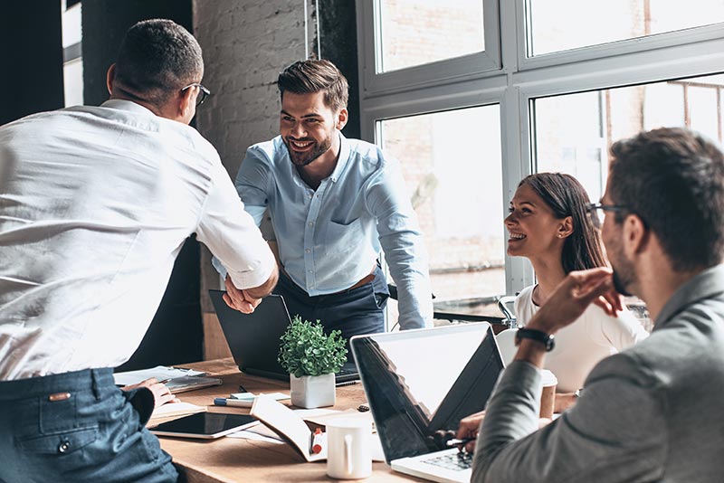 group at conference table shaking hands